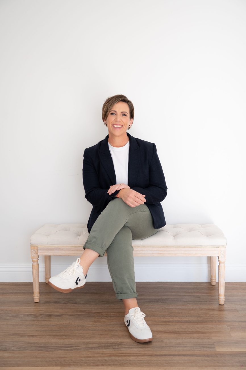 Anita Gibbons sitting on a bench, smiling, wearing a navy blazer
