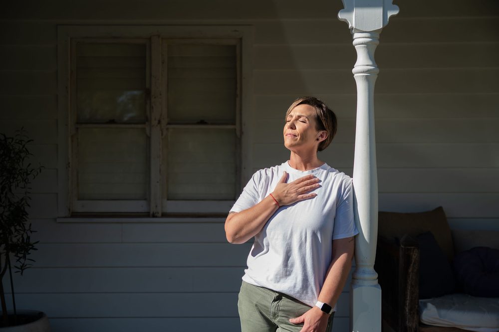 Anita Gibbons standing quietly with her eyes closed and a hand on her heart